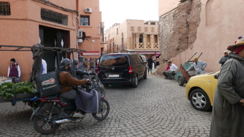 Zu sehen ist eine Straße mit Autos und Motorrädern im Zentrum Marrakeschs.