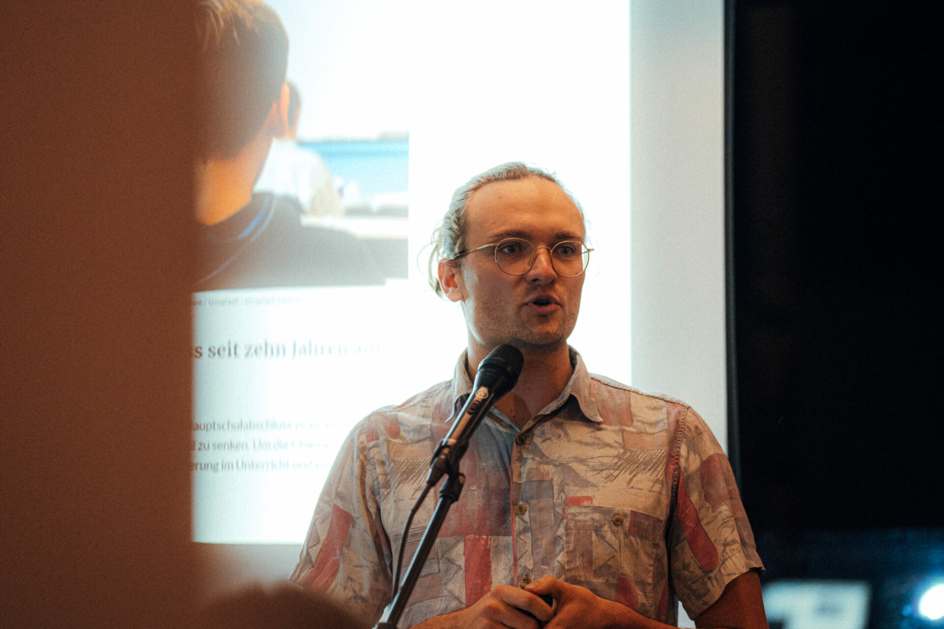 Zu sehen ist Matthias Fischer vor einer Powerpoint-Präsentation.