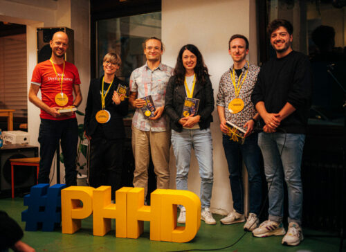Zu sehen sind fünf Wissenschaftler*innen mit Medaillen vor dem Schriftzug #PHHD, daneben Max Wetterauer.