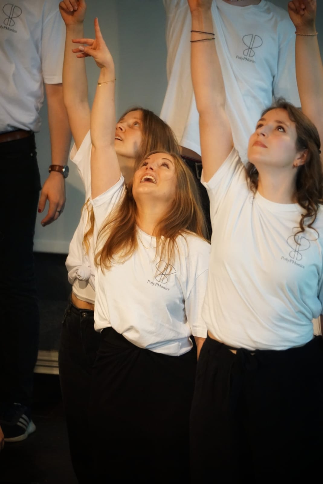 Zu sehen sind mehrere Studierende in weißen T-Shirts singend.