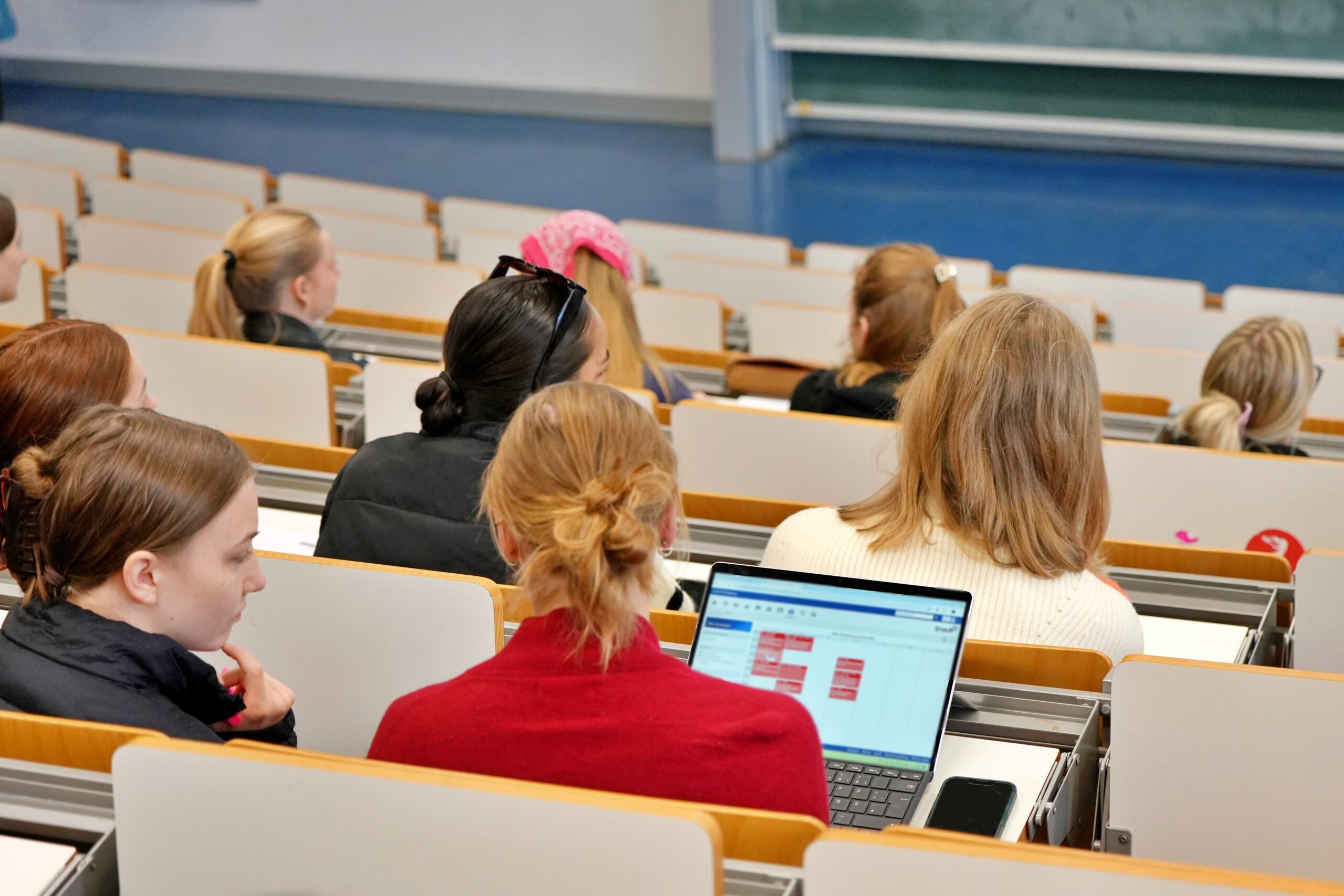 Zu sehen sind Studierende im Hörsaal von hinten mit Blick auf einen Laptop
